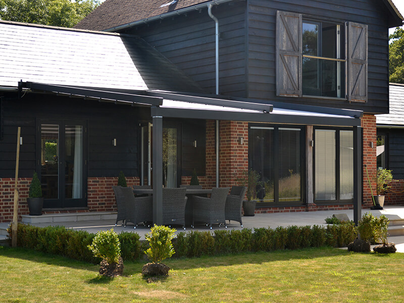 grey awning covering patio on modern barn themed house